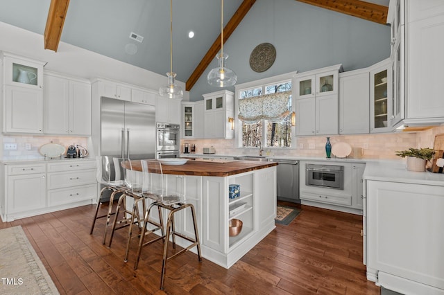 kitchen featuring visible vents, dark wood-style flooring, butcher block countertops, appliances with stainless steel finishes, and a center island