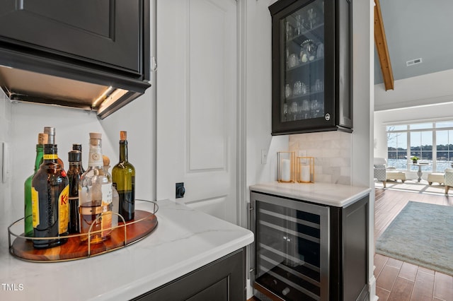 bar with visible vents, beverage cooler, wood finished floors, decorative backsplash, and a dry bar