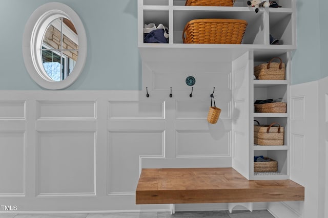 mudroom with built in features and a decorative wall