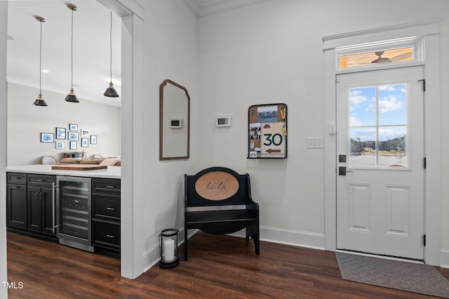 foyer featuring beverage cooler, dark wood finished floors, baseboards, and ornamental molding