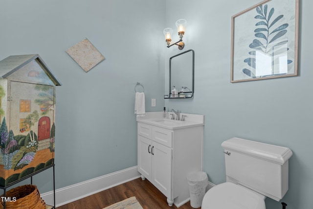 bathroom featuring toilet, vanity, baseboards, and wood finished floors