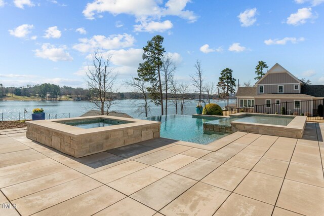 view of pool with a pool with connected hot tub, a patio, and a water view