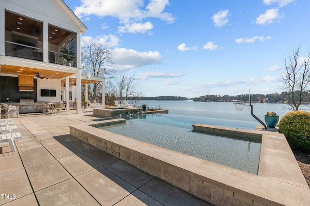 view of swimming pool with a water view, an infinity pool, a ceiling fan, exterior kitchen, and a patio area