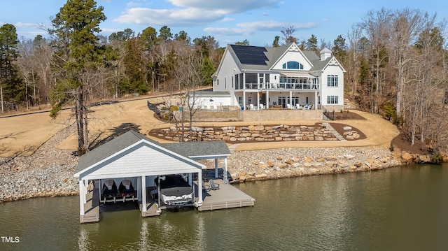 rear view of property featuring a water view, boat lift, and a patio area