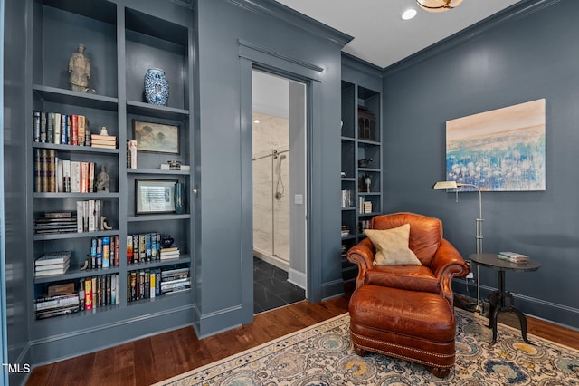 sitting room with built in shelves, baseboards, wood finished floors, and crown molding