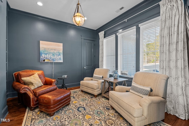 living area with visible vents, crown molding, and wood finished floors