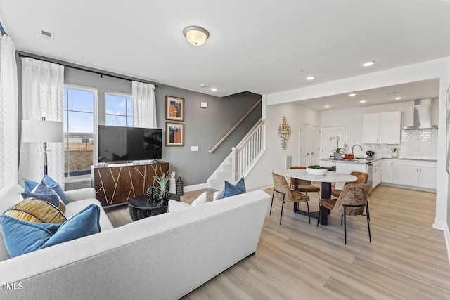 living room featuring visible vents, light wood-style flooring, recessed lighting, stairway, and baseboards