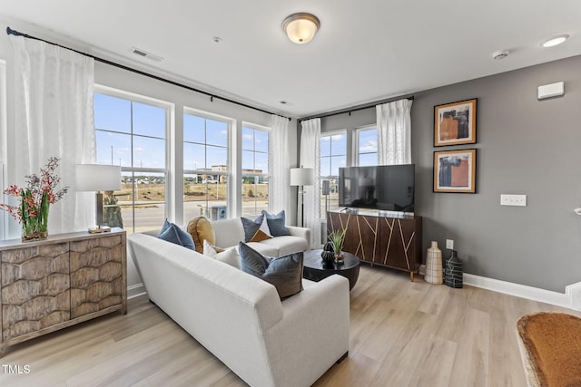 living area featuring visible vents, baseboards, and wood finished floors