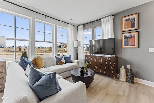 living area with light wood finished floors, visible vents, and baseboards