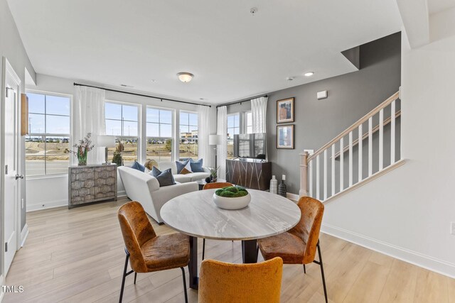 dining room with light wood-style flooring, stairs, and baseboards