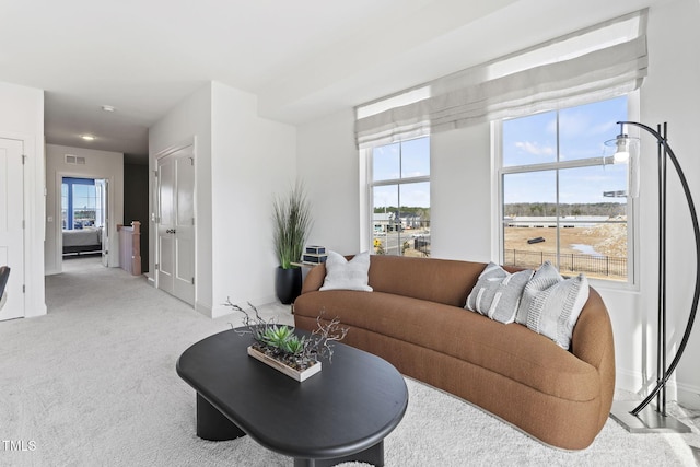 living room with visible vents, light colored carpet, and baseboards