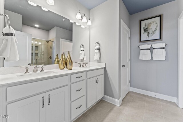 full bathroom with tile patterned flooring, double vanity, a stall shower, and a sink