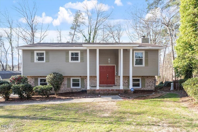 split foyer home featuring a front yard, brick siding, and a chimney