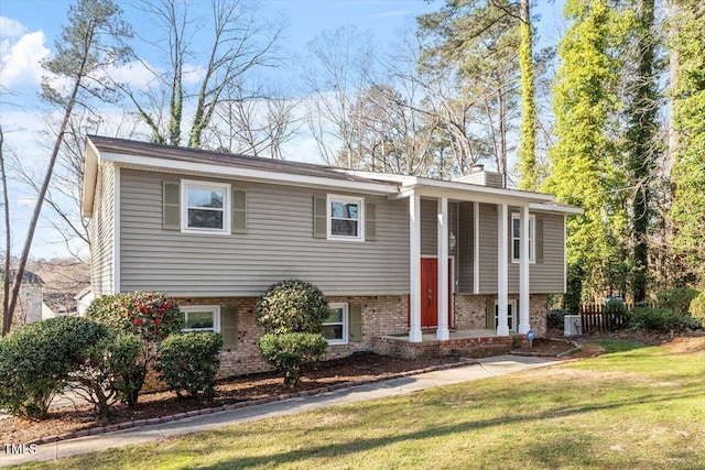 bi-level home with a front lawn, central air condition unit, brick siding, and a chimney