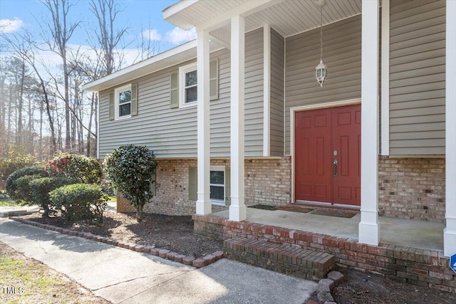 entrance to property with a porch and brick siding