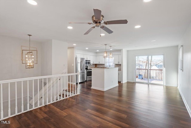 unfurnished living room featuring dark wood finished floors, ceiling fan with notable chandelier, recessed lighting, and baseboards