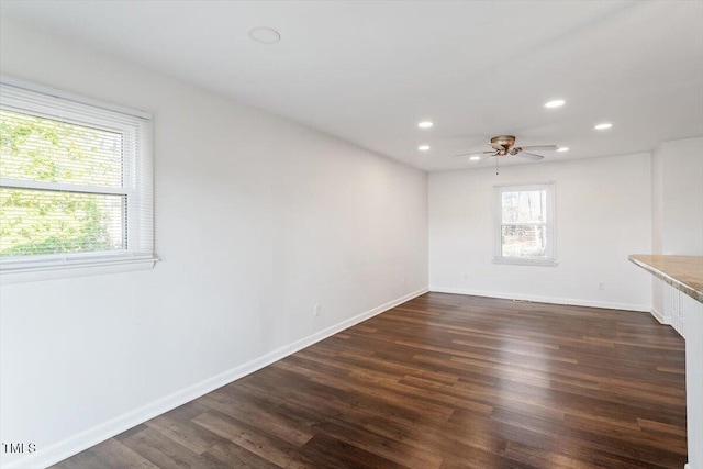 unfurnished room featuring dark wood finished floors, recessed lighting, baseboards, and a wealth of natural light