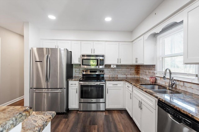 kitchen with a sink, stainless steel appliances, backsplash, and dark wood finished floors