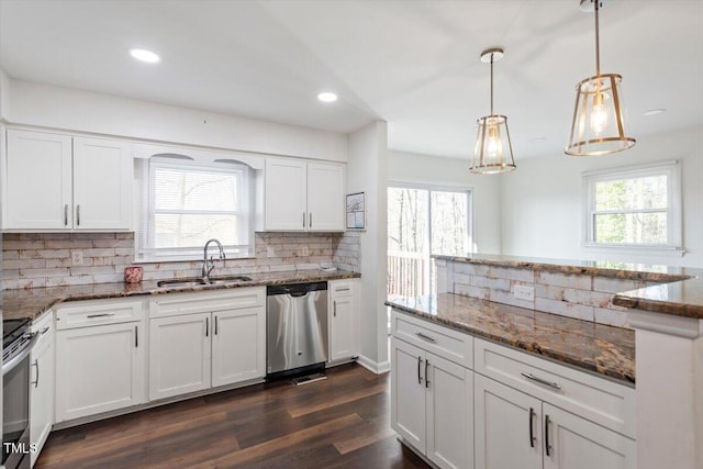 kitchen featuring dark stone counters, a wealth of natural light, appliances with stainless steel finishes, and a sink