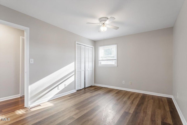 unfurnished bedroom featuring visible vents, baseboards, wood finished floors, a closet, and a ceiling fan