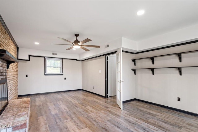 unfurnished living room with visible vents, brick wall, and light wood-type flooring