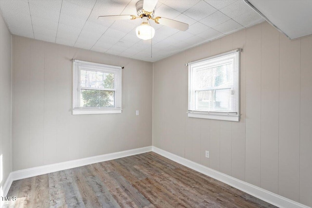 spare room featuring baseboards, wood finished floors, and a ceiling fan