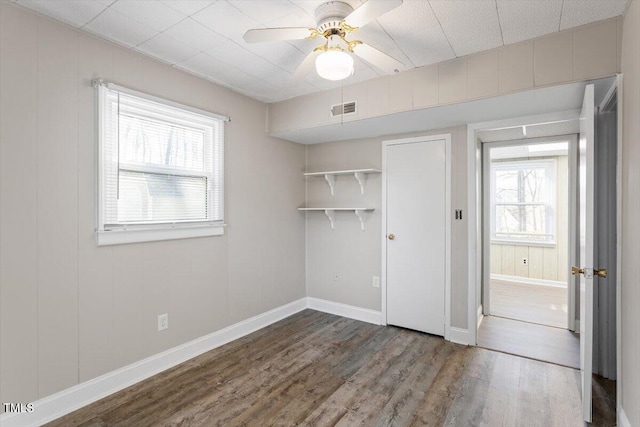 unfurnished bedroom featuring a ceiling fan, wood finished floors, visible vents, and baseboards