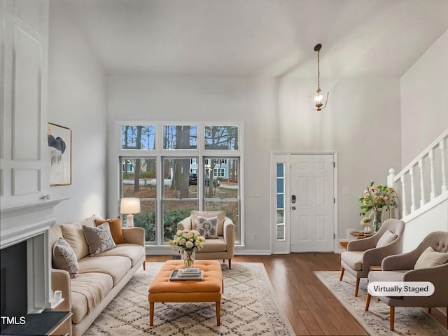 living room featuring baseboards, stairway, a fireplace, a high ceiling, and dark wood-style flooring