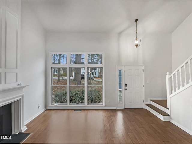 foyer with hardwood / wood-style floors, visible vents, baseboards, a fireplace, and stairs