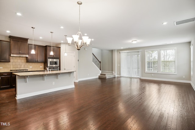 kitchen with a kitchen bar, visible vents, open floor plan, dark wood-style floors, and stainless steel appliances