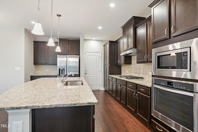 kitchen featuring dark brown cabinets, under cabinet range hood, dark wood finished floors, appliances with stainless steel finishes, and a sink