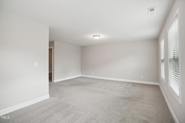 carpeted spare room featuring visible vents and baseboards