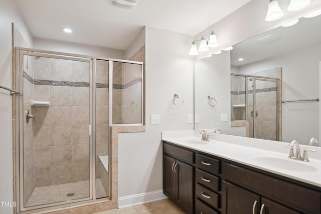 bathroom featuring double vanity, a stall shower, tile patterned floors, and a sink