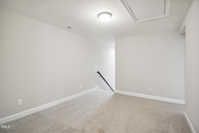 carpeted empty room featuring visible vents, baseboards, and attic access