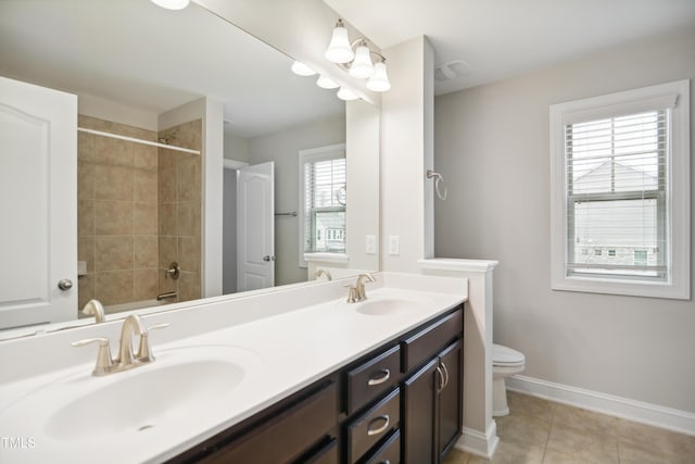 bathroom with double vanity, toilet, baseboards, and a sink