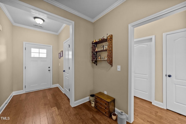 entryway featuring visible vents, wood finished floors, baseboards, and ornamental molding