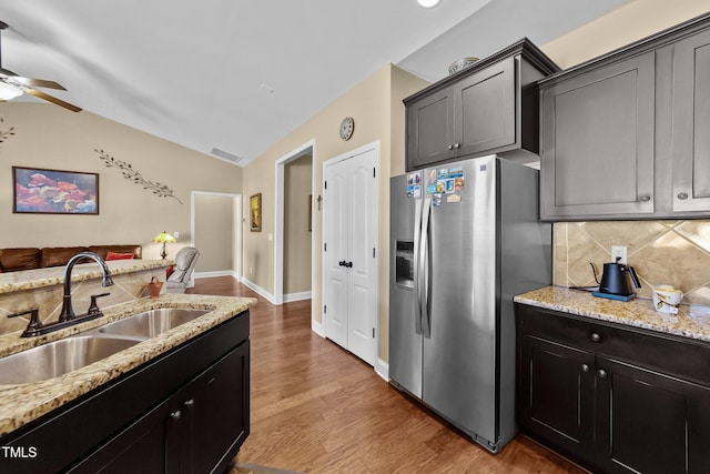 kitchen featuring a sink, backsplash, stainless steel fridge, ceiling fan, and vaulted ceiling