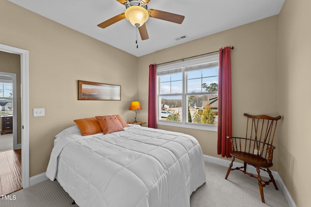 bedroom featuring visible vents, baseboards, light colored carpet, and a ceiling fan