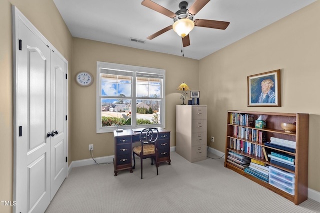 office featuring baseboards, a ceiling fan, visible vents, and light carpet