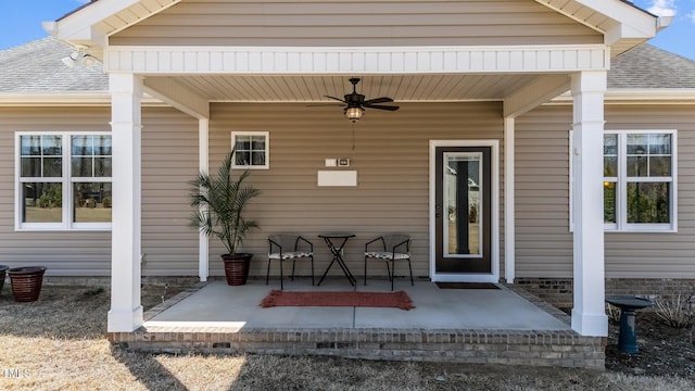 doorway to property featuring roof with shingles and ceiling fan