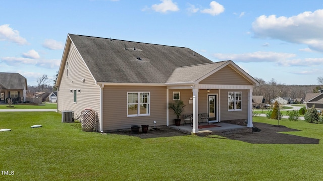 back of house featuring a lawn, roof with shingles, and a patio area