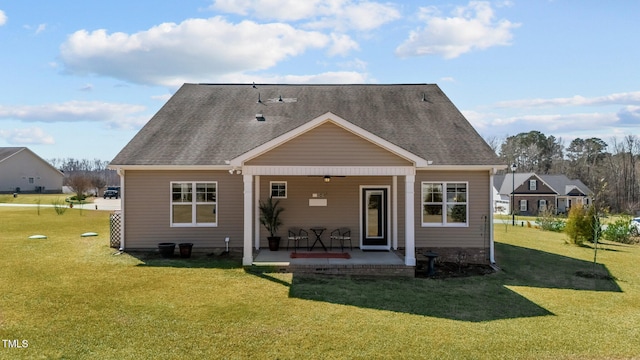 rear view of property with a lawn, a patio, ceiling fan, and roof with shingles