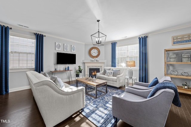 living area featuring visible vents, crown molding, baseboards, a glass covered fireplace, and dark wood-style flooring