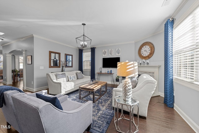 living room with a healthy amount of sunlight, wood finished floors, baseboards, and decorative columns