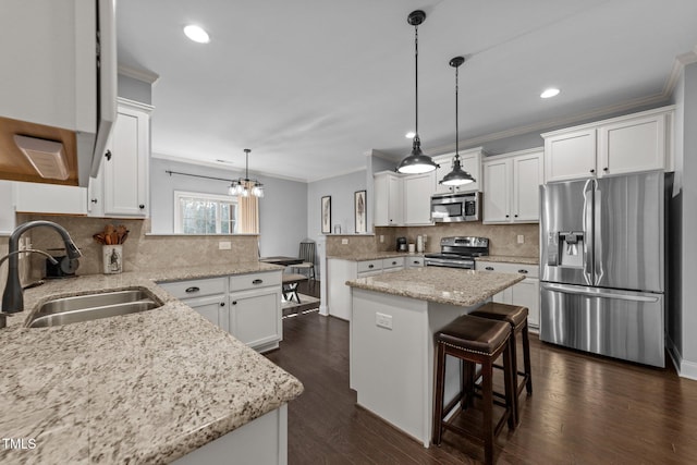 kitchen with a sink, dark wood-style floors, appliances with stainless steel finishes, a peninsula, and crown molding