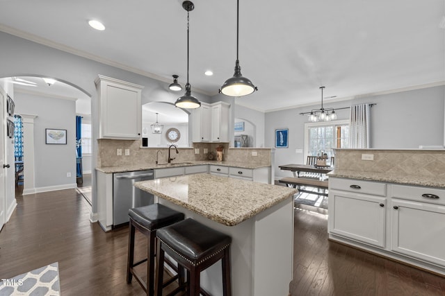 kitchen with a kitchen island, crown molding, stainless steel dishwasher, arched walkways, and dark wood-style flooring