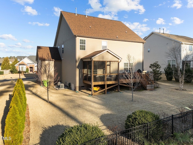 back of property with a shingled roof, a wooden deck, fence, and crawl space