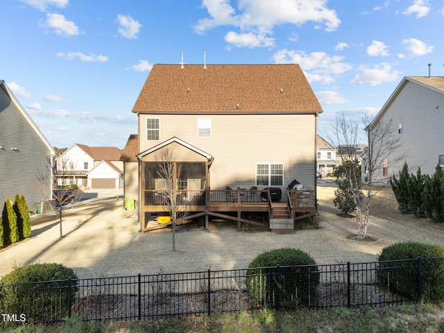 rear view of property with a wooden deck, a shingled roof, and fence