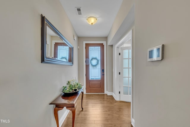 doorway to outside featuring visible vents, light wood-type flooring, and baseboards