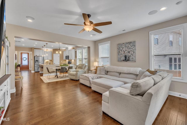 living room with recessed lighting, wood finished floors, baseboards, and a healthy amount of sunlight